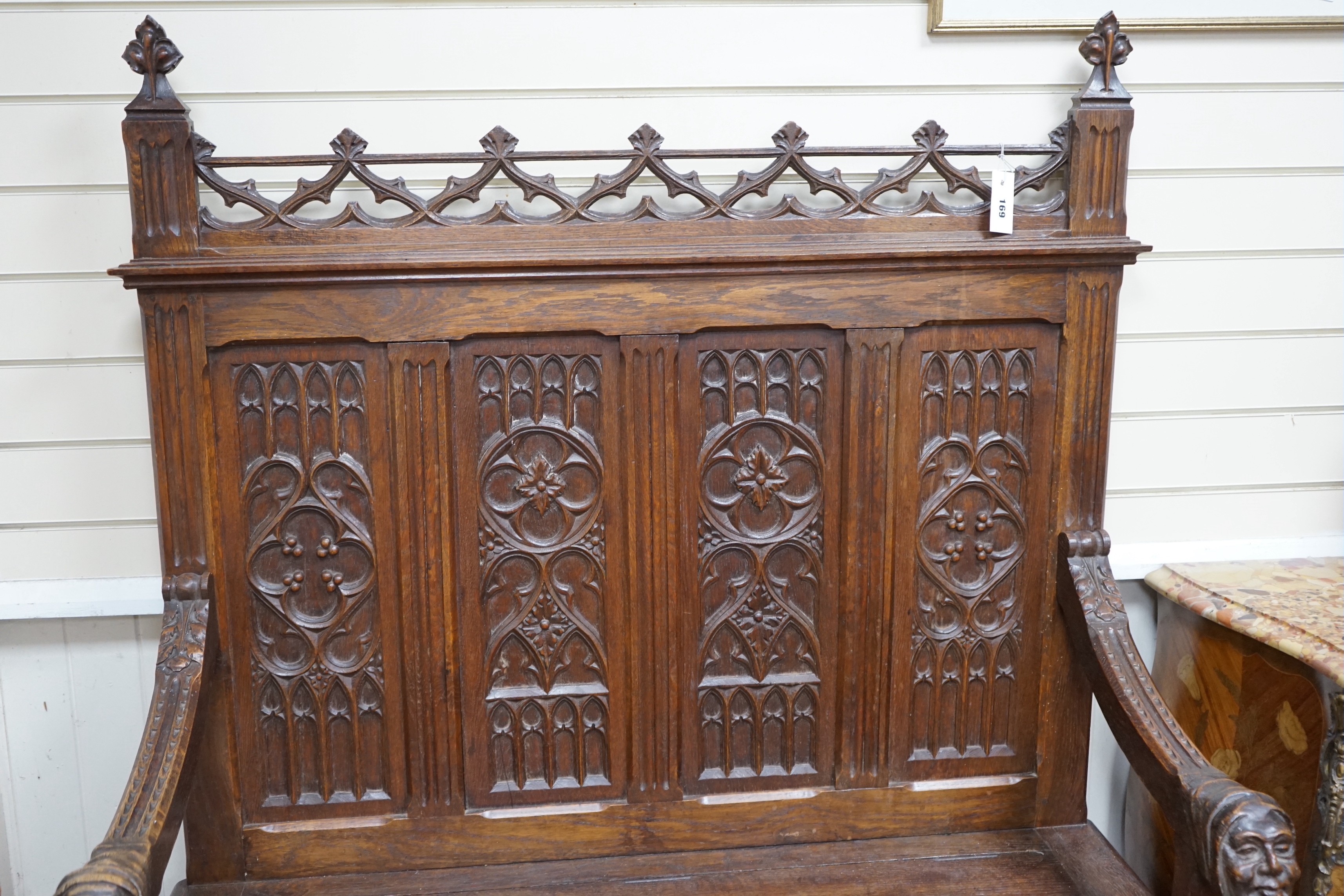 An early 20th century Gothic style carved oak box seat settle, length 116cm, depth 45cm, height 154cm